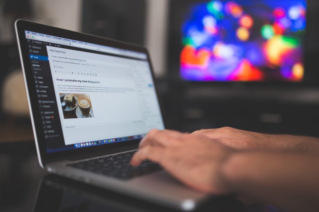 A person typing a blog post on a laptop.  